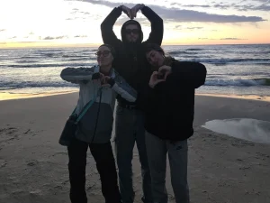 Tres jóvenes en la playa posando haciendo un corazón