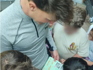 Chico con niños enseñando un cuaderno