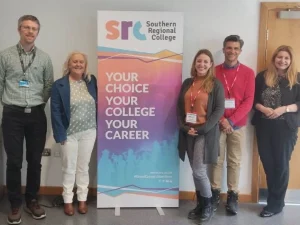 Grupo de profesores al lado de un cartel indicando el Southern Regional College