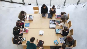Grupo de estudiantes trabajando juntos alrededor de una gran mesa.